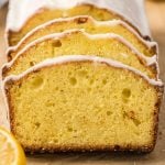 Close-up of three slices of glazed lemon pound cake, inspired by the Starbucks Lemon Loaf Recipe, arranged in a row to reveal the moist, yellow interior and light icing, with part of a fresh lemon visible in the corner.
