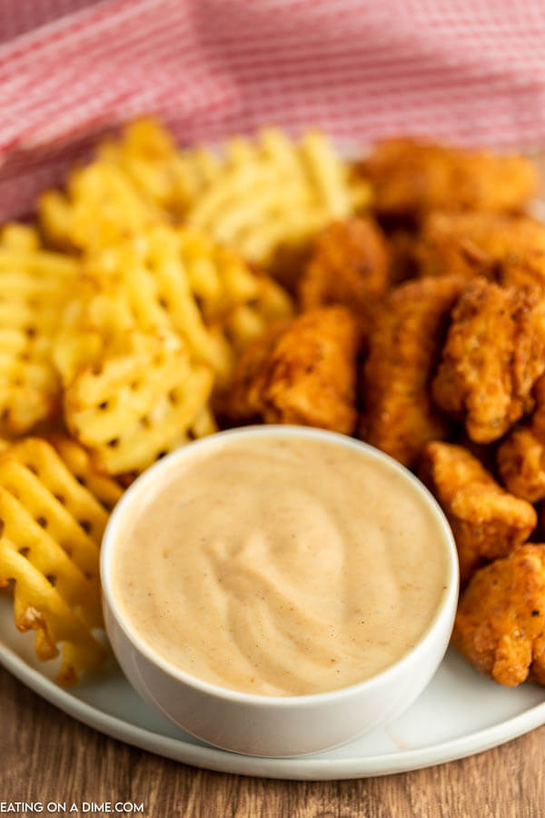 Close up image of honey roasted bbq sauce with a side of chicken nuggets and french fries on a plate. 
