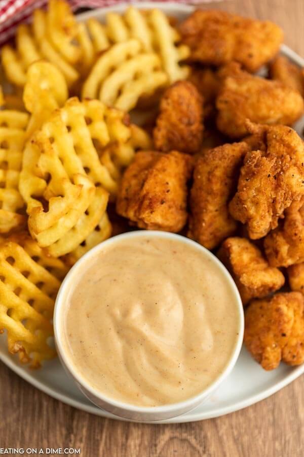 Close up image of honey roasted bbq sauce with a side of chicken nuggets and french fries on a plate. 