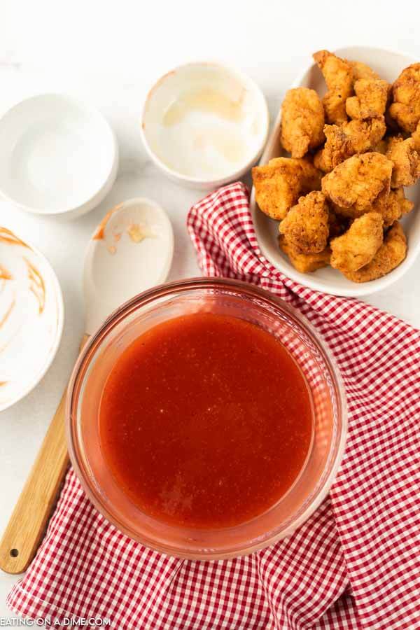 Close up image of polynesian sauce in a bowl with a chicken nuggets on the side. 