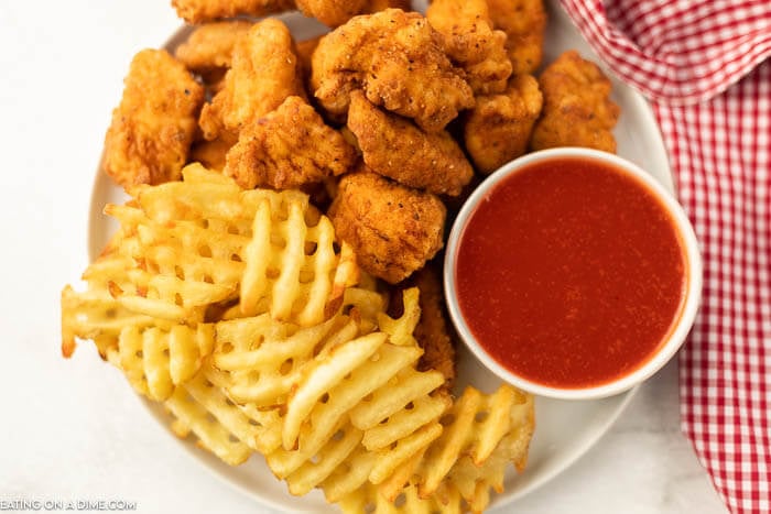 Close up image of polynesian sauce with a side of fries and chicken nuggets