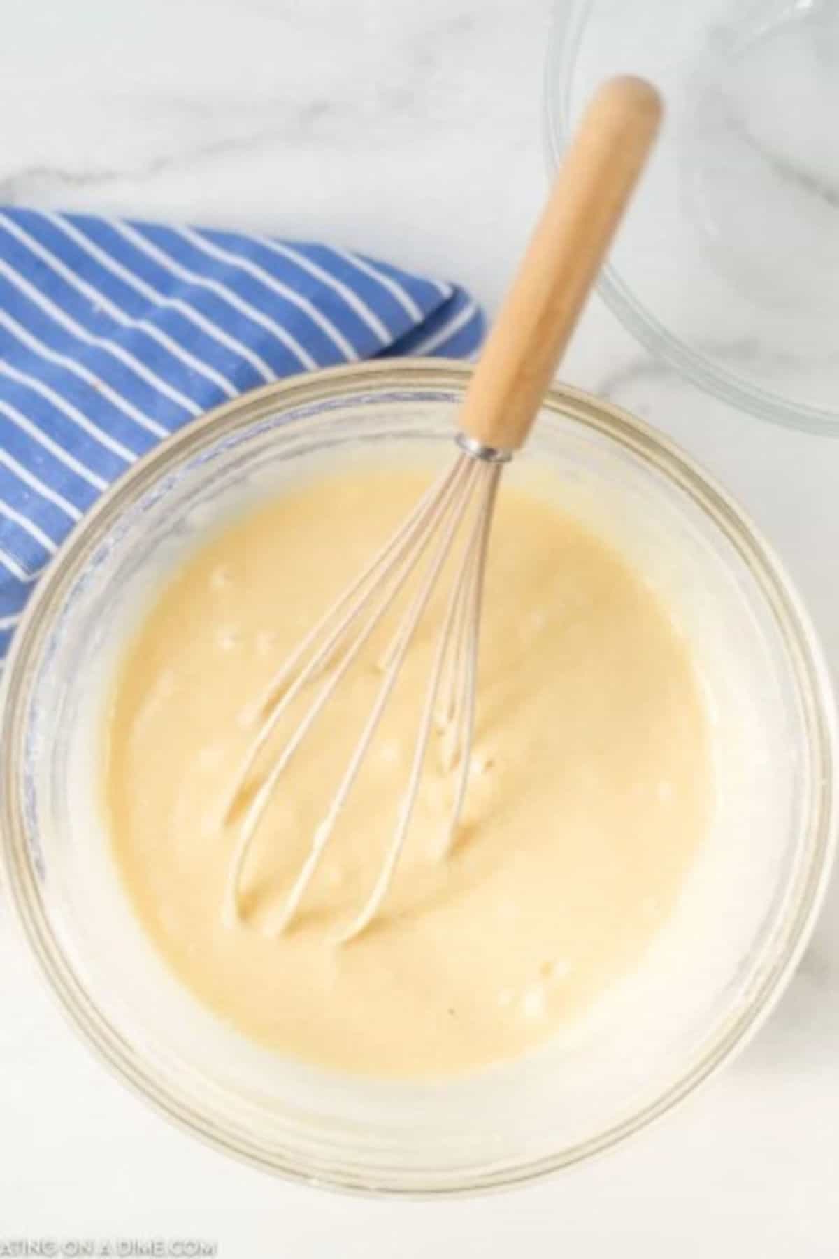 The process of mixing the bread batter in a clear bowl with a whisk.