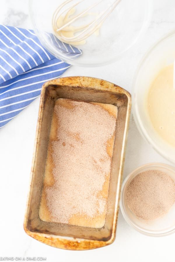 The process of adding the cinnamon mixture in the pan with the bread batter. 