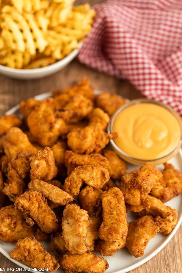 Close up image of a plate of spicy chicken nuggets with a side of honey mustard dipping sauce. 