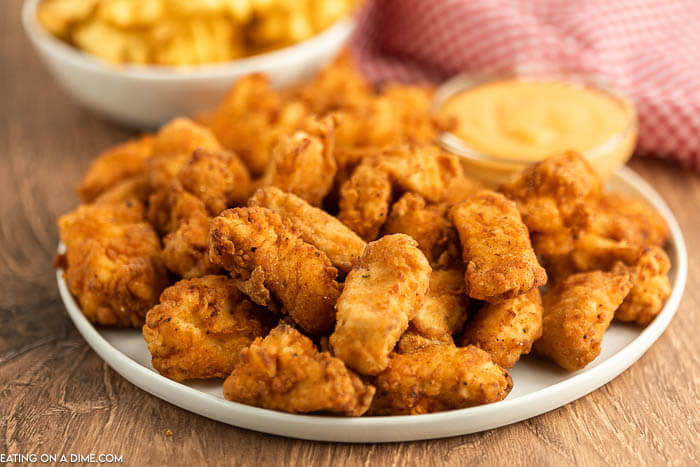 Close up image of a plate of spicy chicken nuggets with a side of honey mustard dipping sauce. 