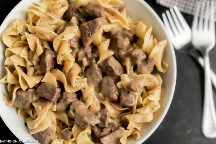 Close up image of a bowl of beef burgundy over noodles with two forks. 