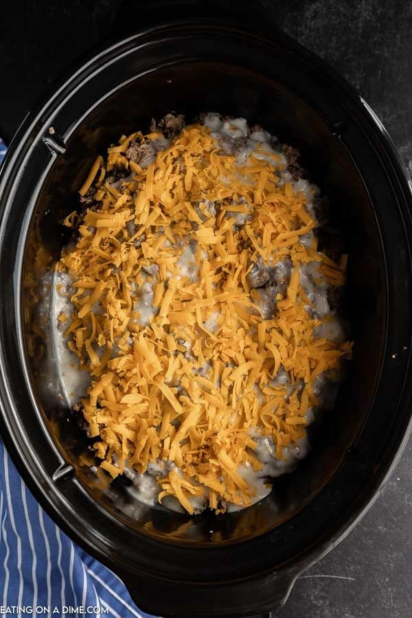Laying the ground beef, slice potatoes and shredded cheese in the slow cooker