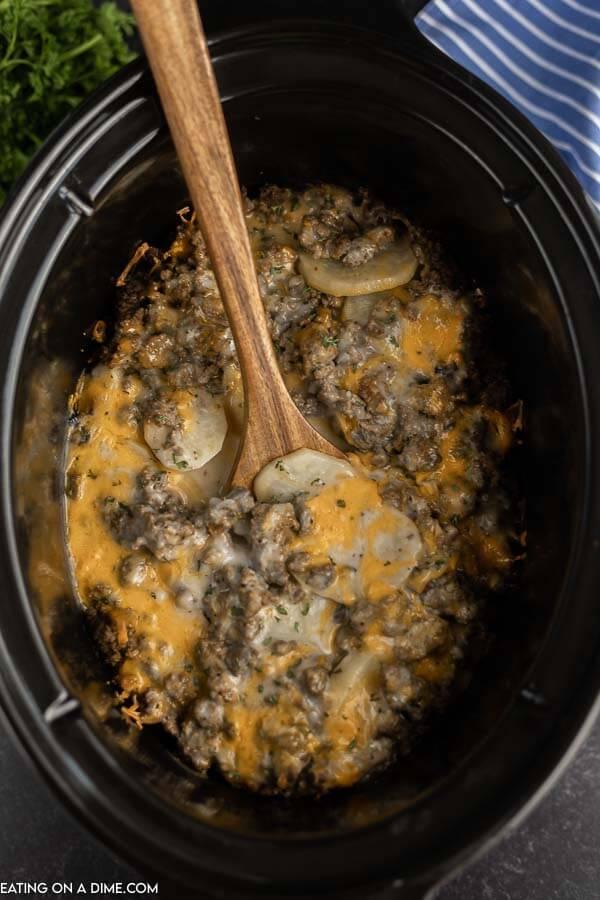Close up image of crock pot hamburger potato casserole with wooden spoon