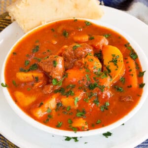 Bowl of Irish stew in a white bowl topped with fresh parsely.