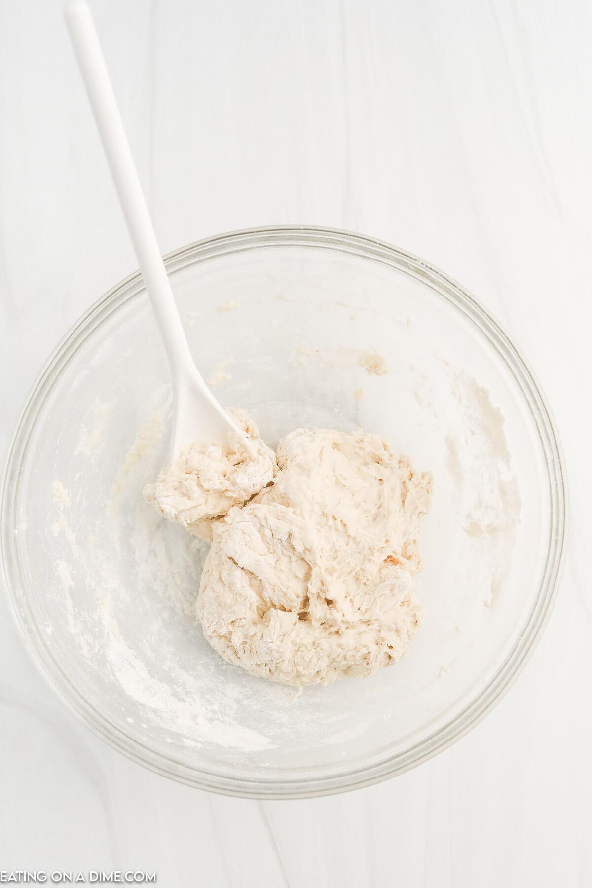 Adding warm water to dry ingredients to create a dough