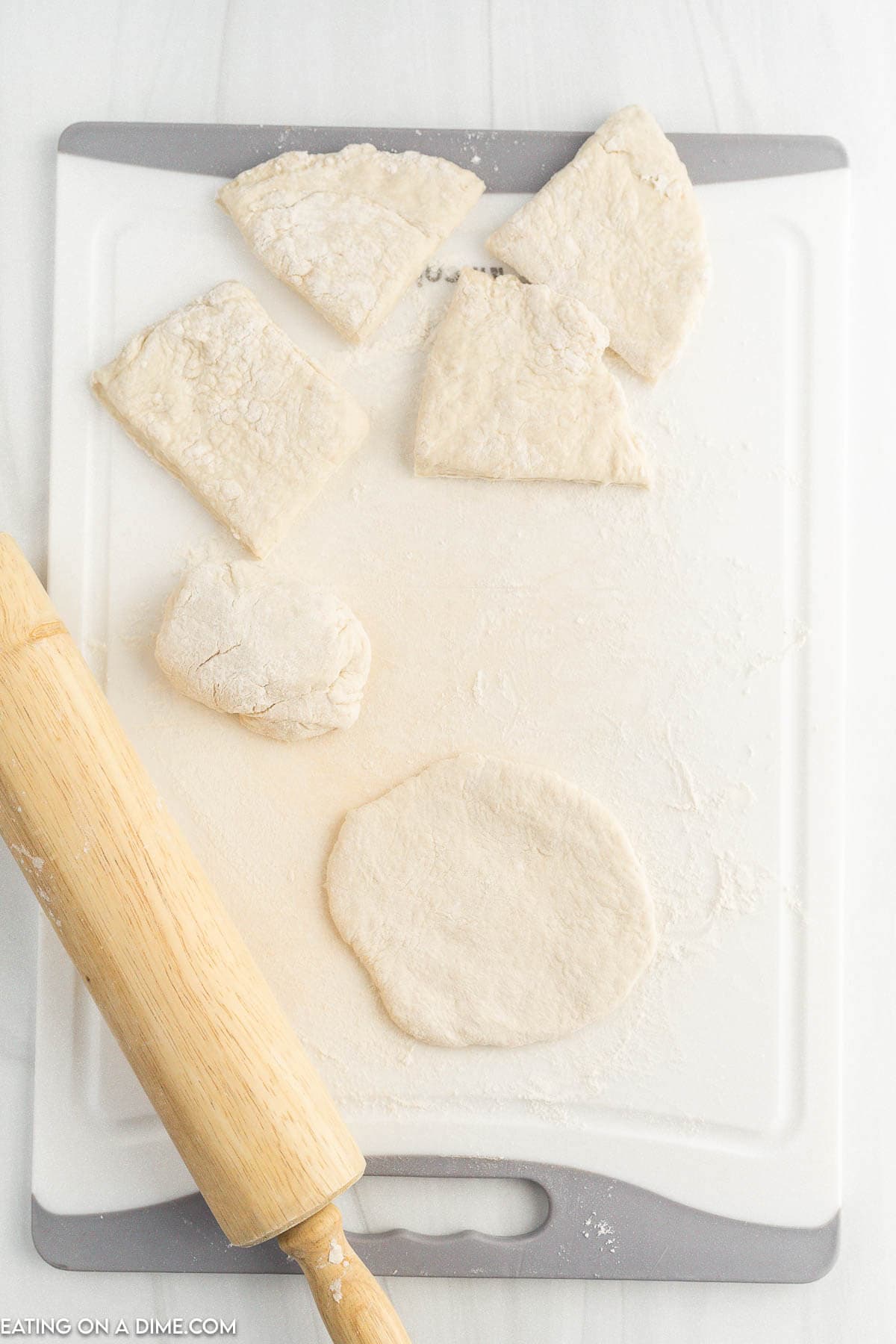 Rolling dough to flatten with a rolling pin on the cutting board