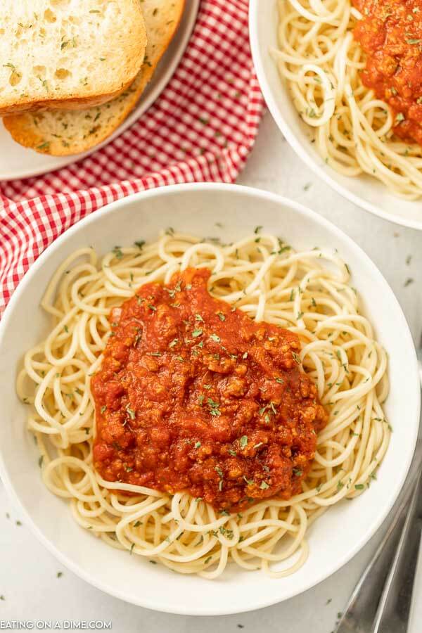 Close up image of a plate of spaghetti noodles with spaghetti sauce on top with two forks on the side, 