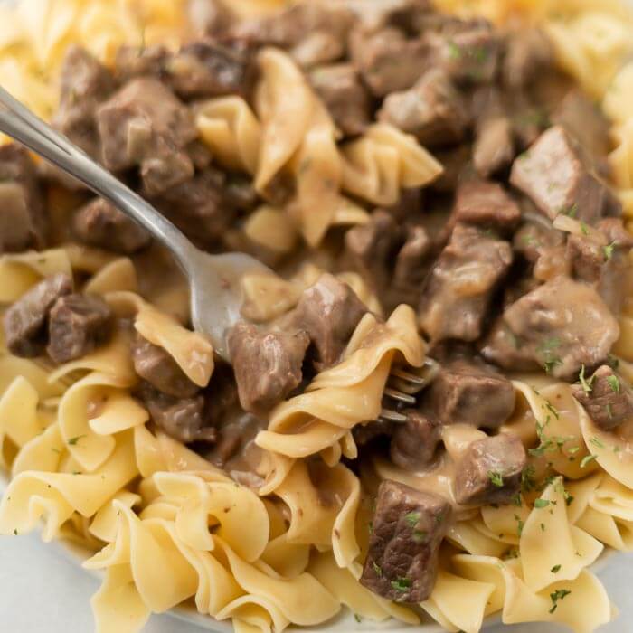 Close up image of Beef Burgundy over noodles with a serving on a fork
