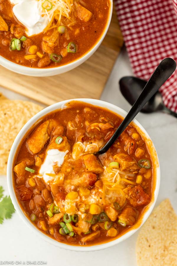 A bowls of this Tex Mex Chicken Chili with the toppings mixed into the chili with a spoon 