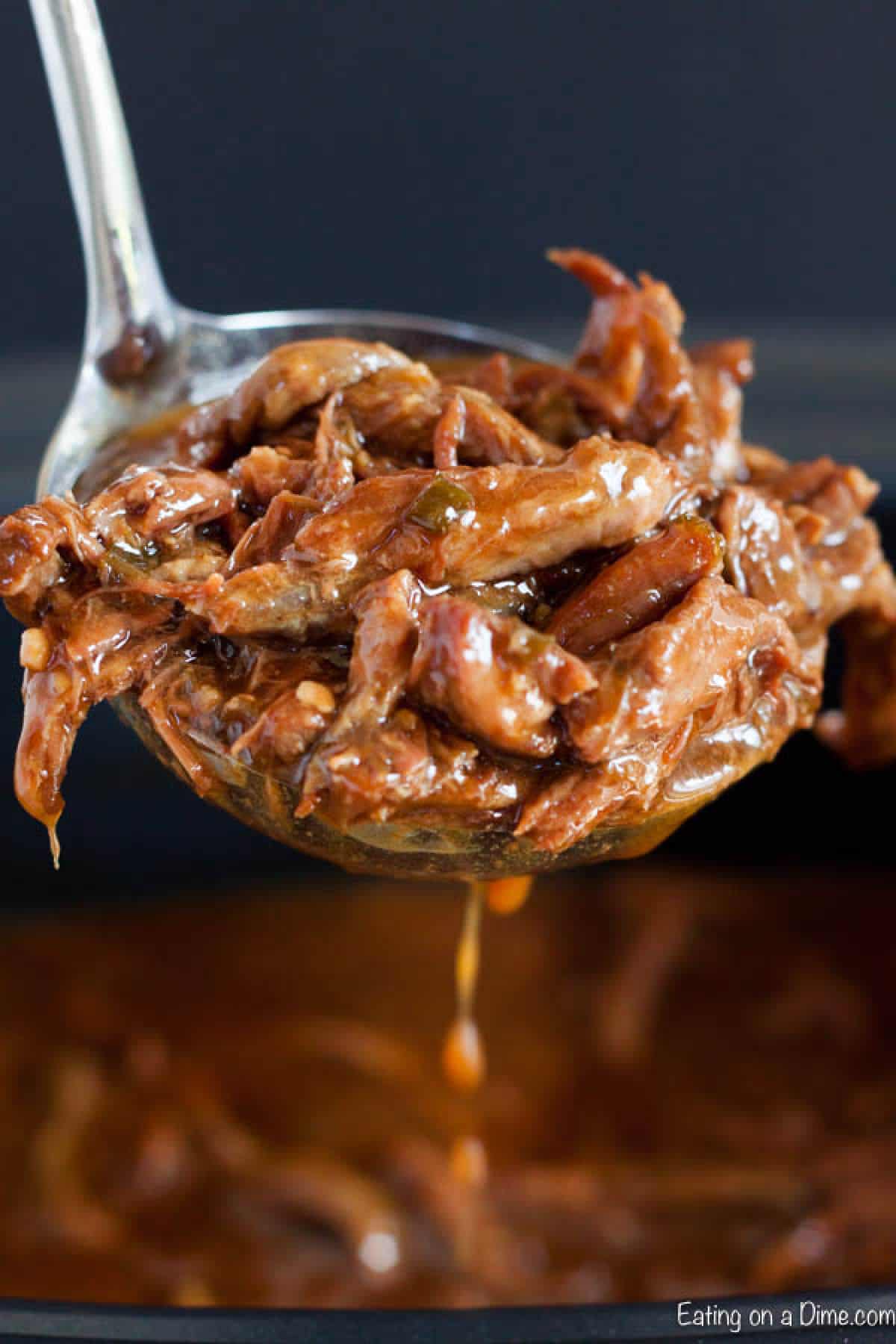 Close up image of sesame beef being dished out of a crock pot.
