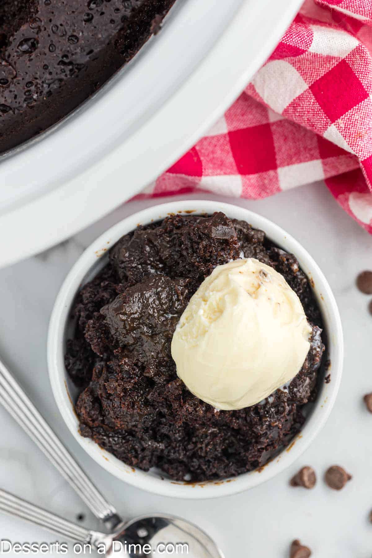 Chocolate lava cake in a white bowl topped with ice cream