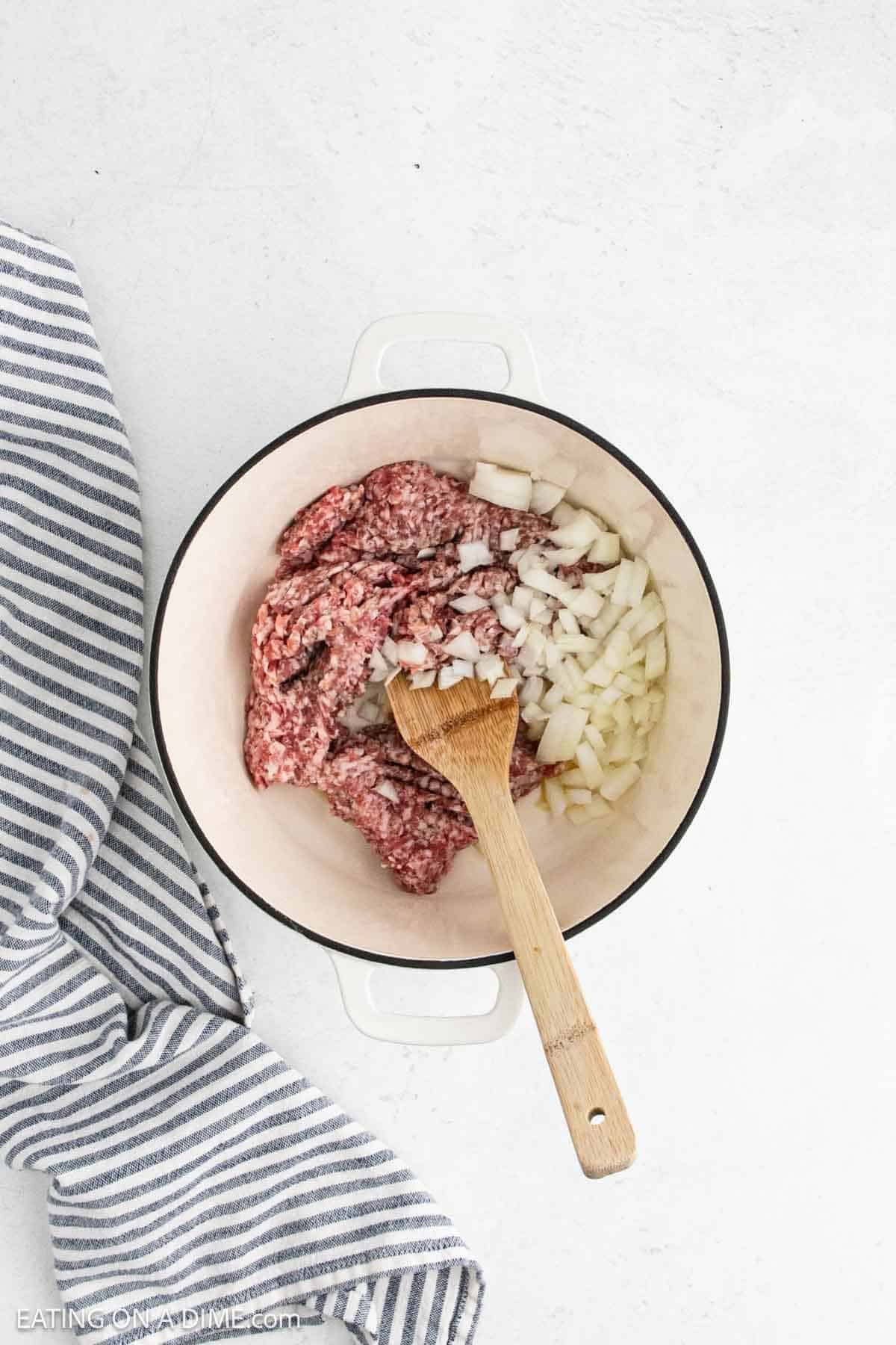 Cooking Italian sausage in a large pot with chopped onions.