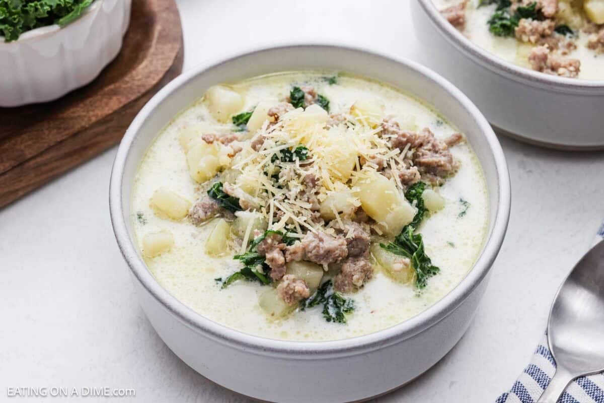 A bowl of zuppa toscana soup topped with shredded parmesan cheese.