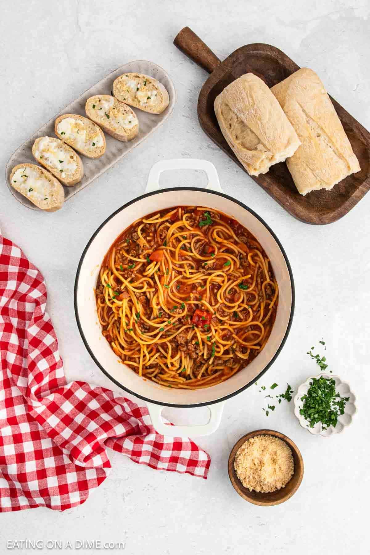 Spaghetti and meat sauce in a large pot with a side of French bread.