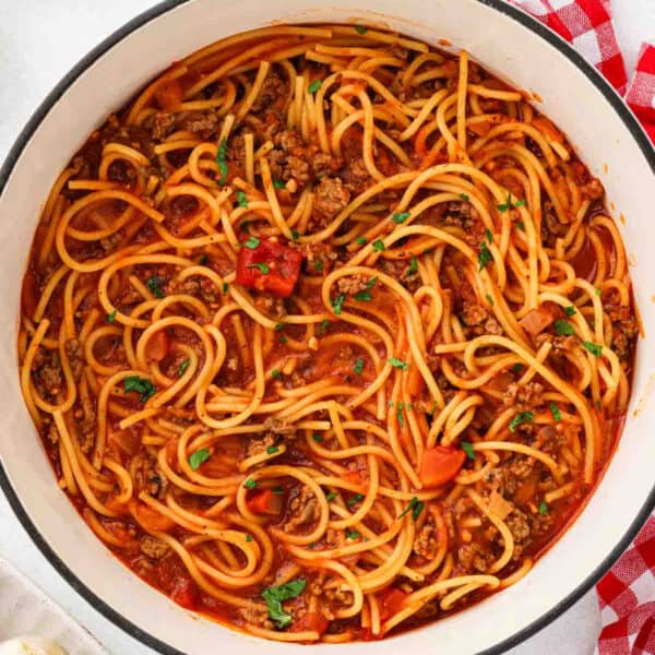 Spaghetti covered in meat sauce in a large pot.