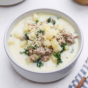 Bowl of Zuppa Toscana Soup topped with shredded parmesan cheese.