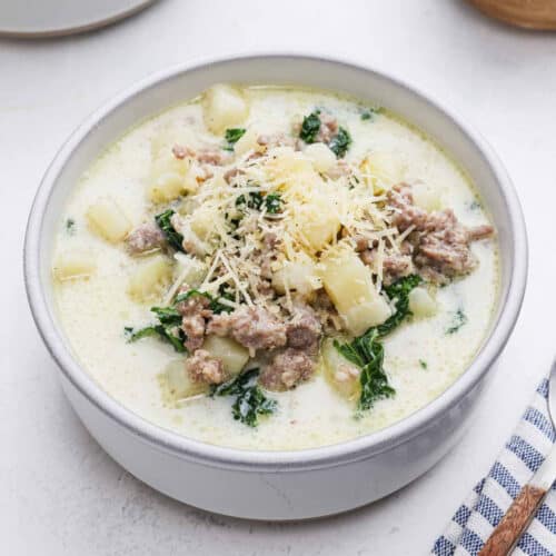 Bowl of Zuppa Toscana Soup topped with shredded parmesan cheese.
