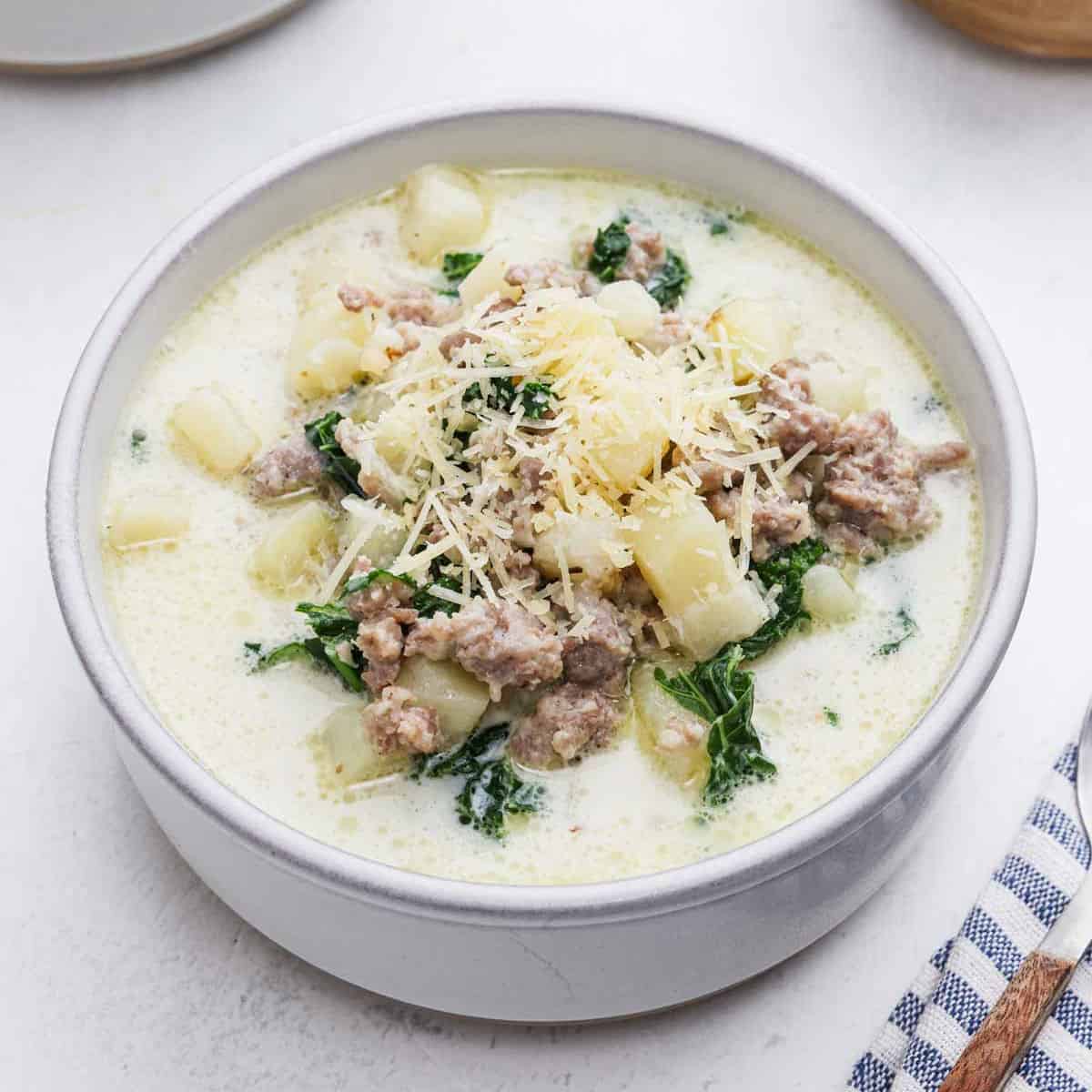 Bowl of Zuppa Toscana Soup topped with shredded parmesan cheese.