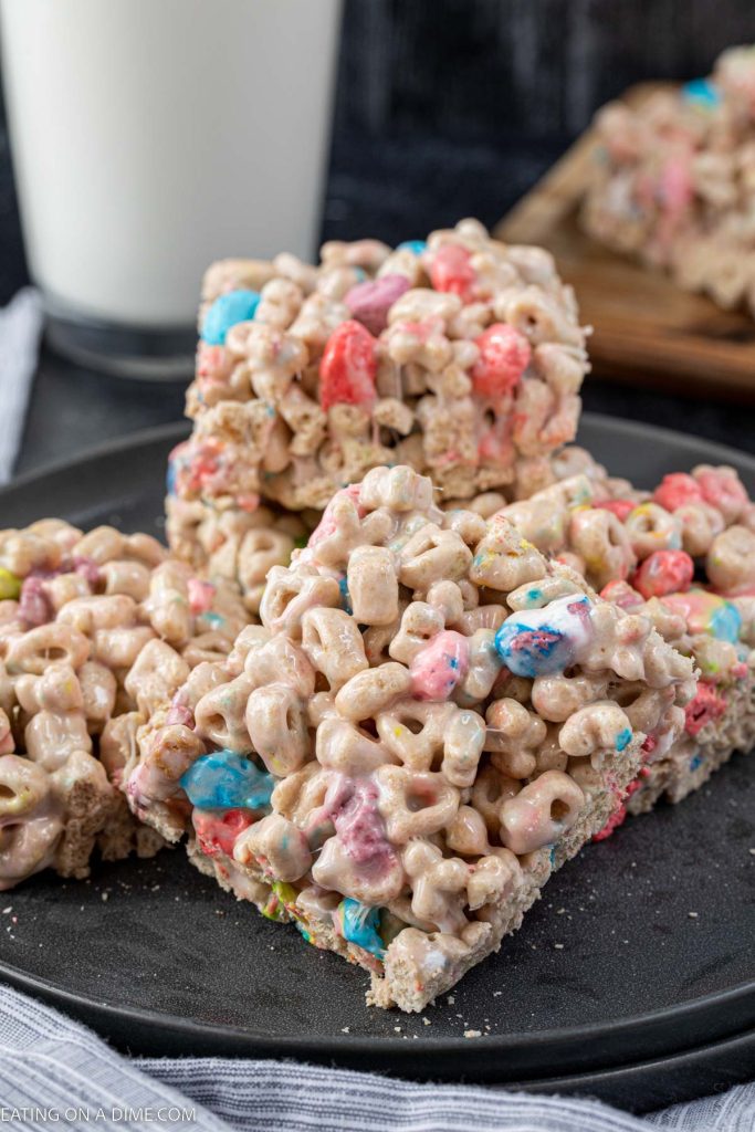 A stack of lucky charm treats on a charcoal plate with a glass of milk behind them.  