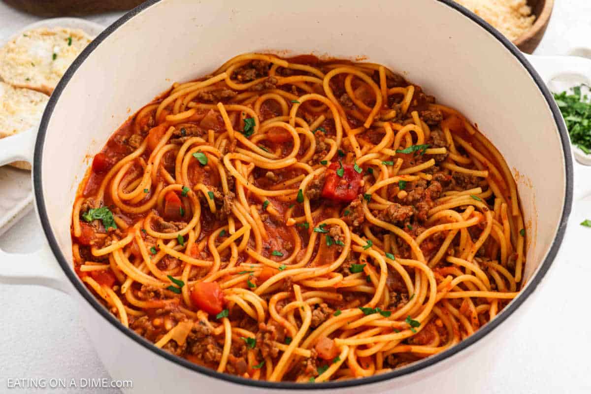 Spaghetti covered in meat sauce in a large pot.