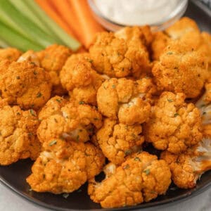 Plate of air fryer cauliflower with celery sticks and carrot sticks.