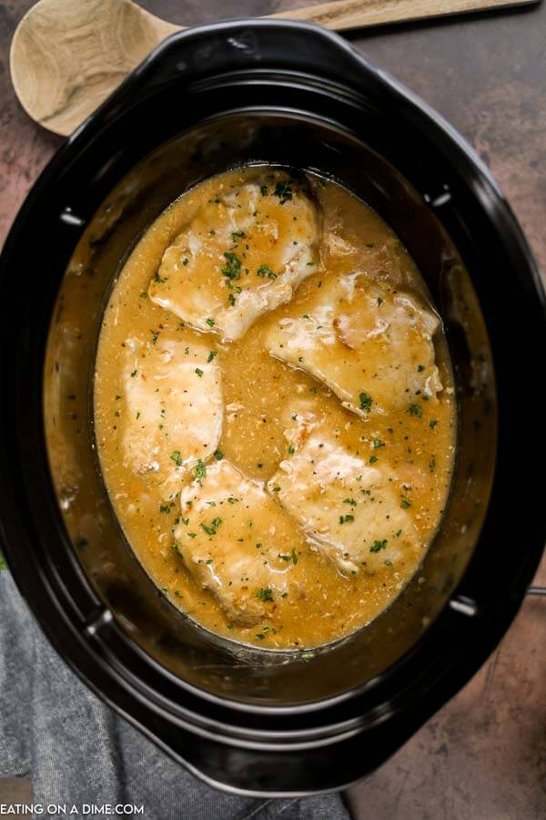 close up image of pork chops and gravy in a crock pot. 