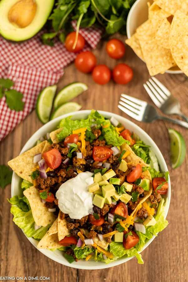 a bowl of taco salad topped with sour cream and diced avocado