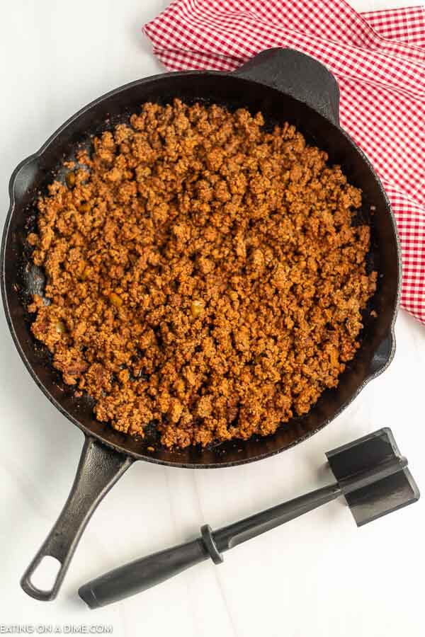 Cooked Ground Beef in a iron skillet with a meat chopper. 