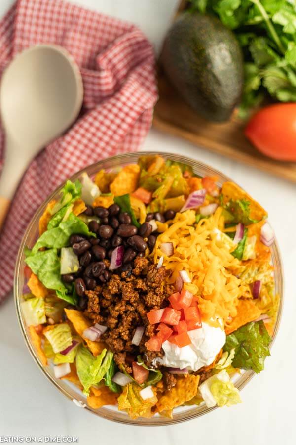 Doritos taco salad in a bowl with a wooden spoon 