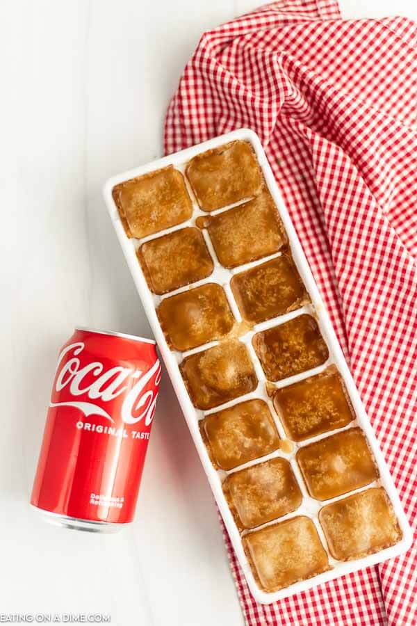A can of coca-cola and an ice tray full of coke ice cubes. 