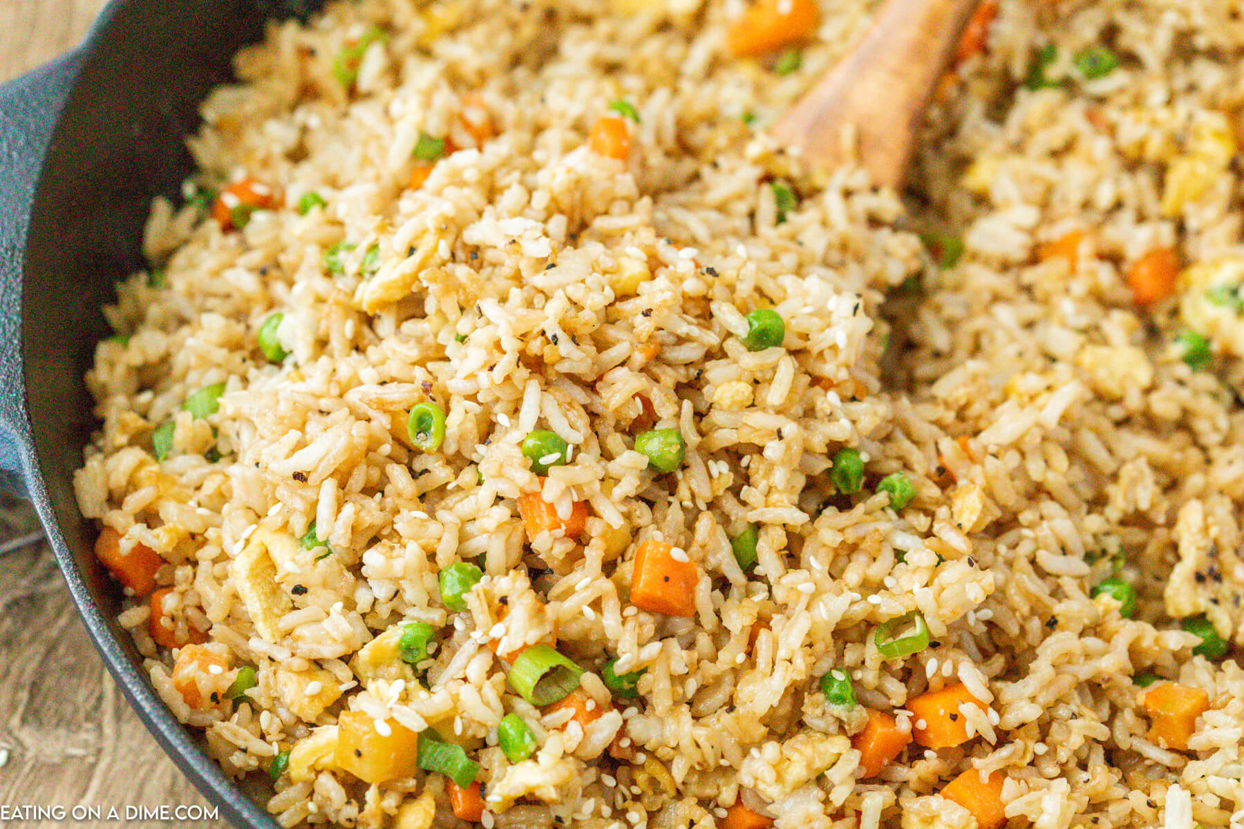 Fried rice in a cast iron skillet with a wooden spoon