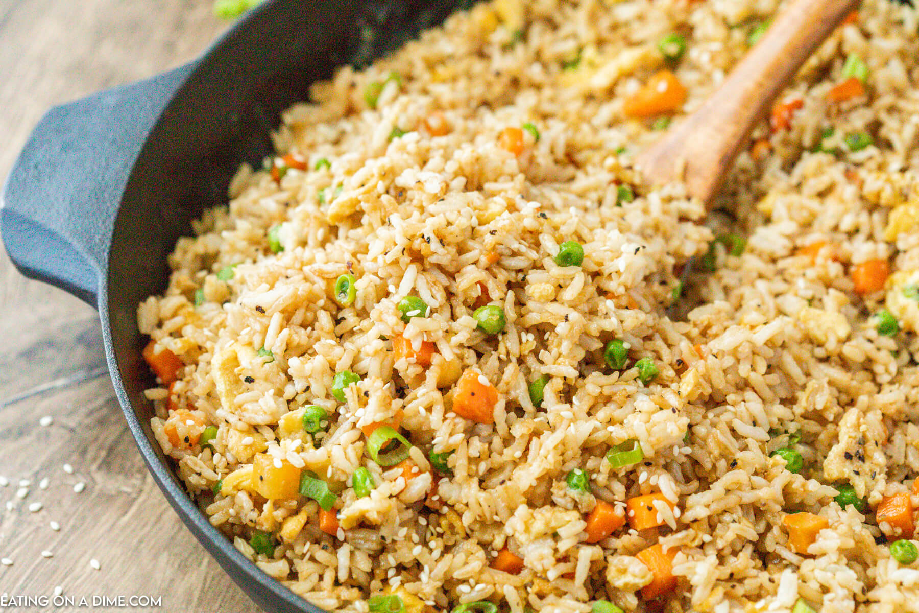 Fried rice in a cast iron skillet in a wooden spoon