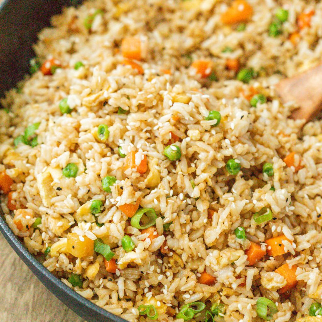 Fried rice in a cast iron skillet with a wooden spoon