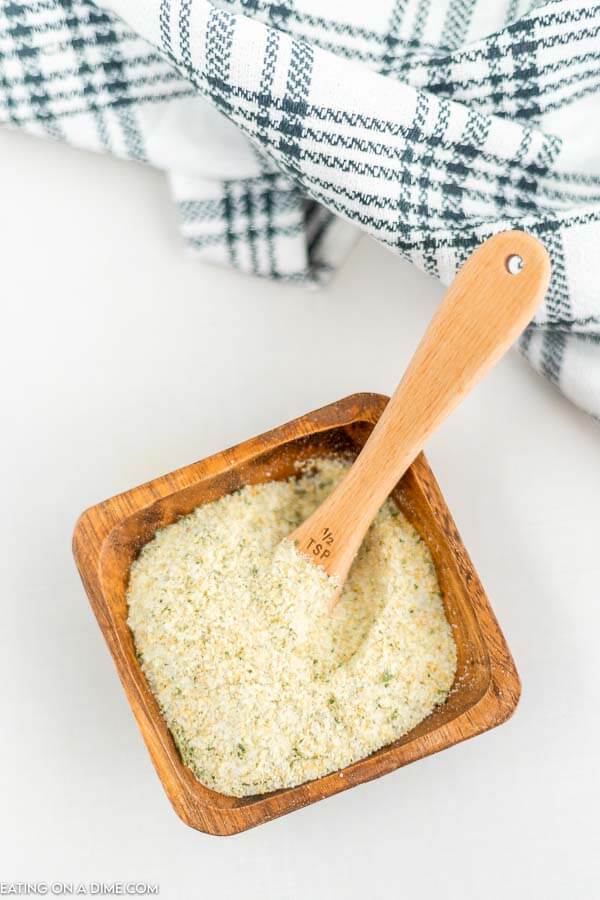 Close up image of a brown dish full of garlic salt and a teaspoon inside the dish