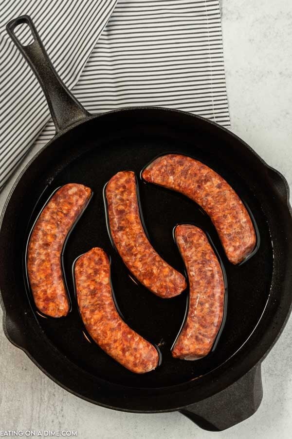 Close up image of italian sausage uncooked in a iron skillet. 