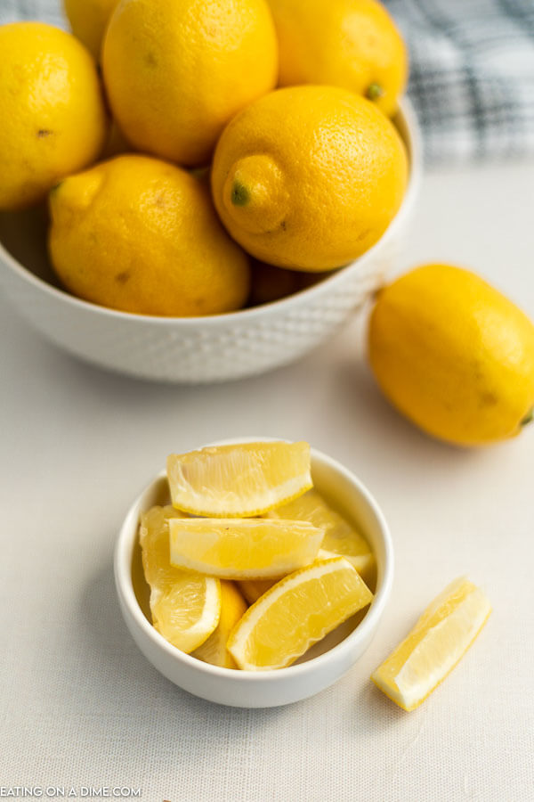 Close up image of a bowl of lemon and a small bowl of lemon wedges. 