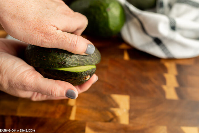 The process of twisting the avocado to make two halves. 