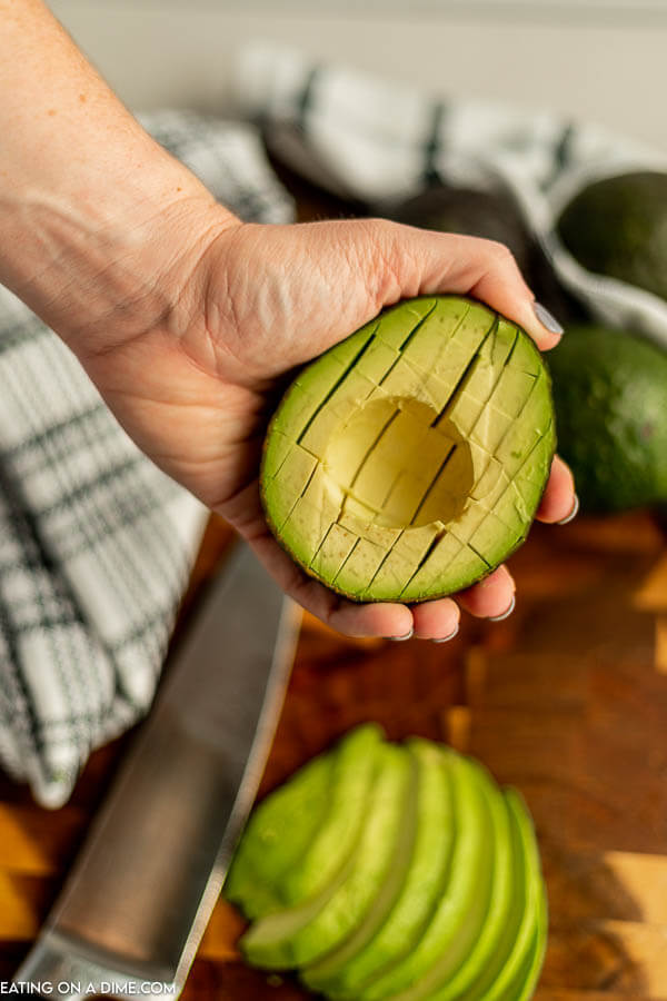 Close up image of avocado chopped in the skin holding in the hand. 