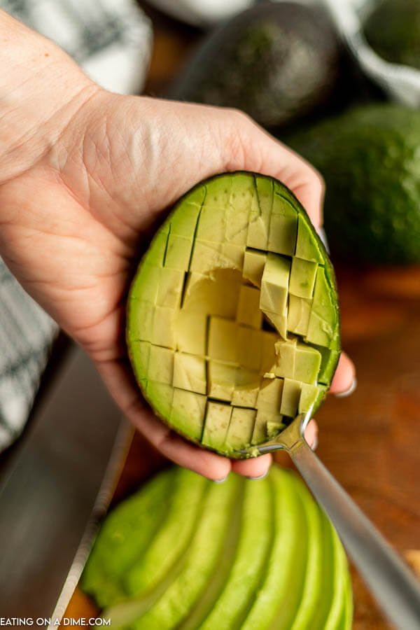 Close up image of holding a avocado half in hand with the avocado diced in skin. 