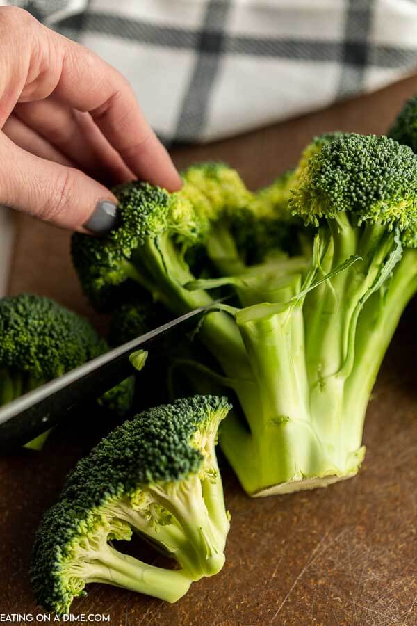 Close up image of broccoli being cut with a knife. 