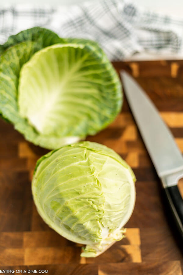 Close up image of whole cabbage on a cutting board with a knife. 