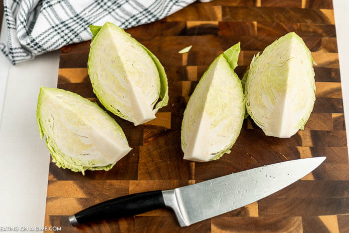Close up image of cabbage wedges on a cutting board with a knife. 