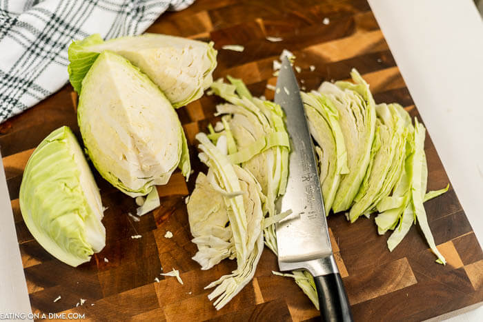 Close up image of sliced cabbage on a cutting board with a knife. 