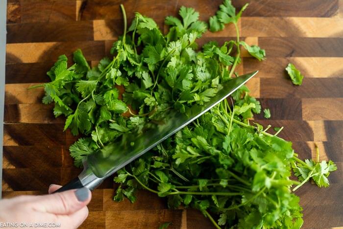 A knife cutting out large leaves from the cilantro stems 