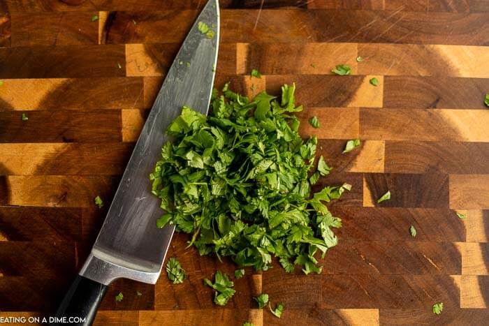 A large knife chopping up the cilantro leaves 